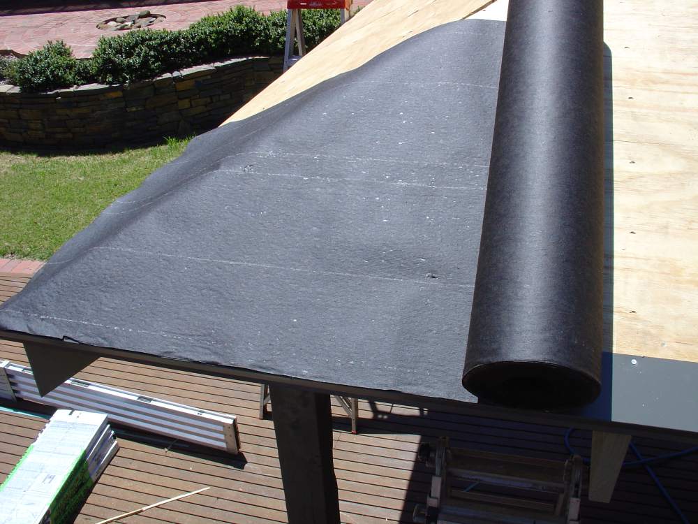 Rolling out asphalt saturated felt underlayment on roof