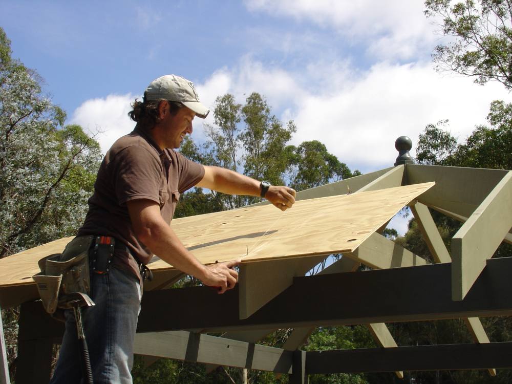 Installing plywood sheeting on gazebo roof during DIY project